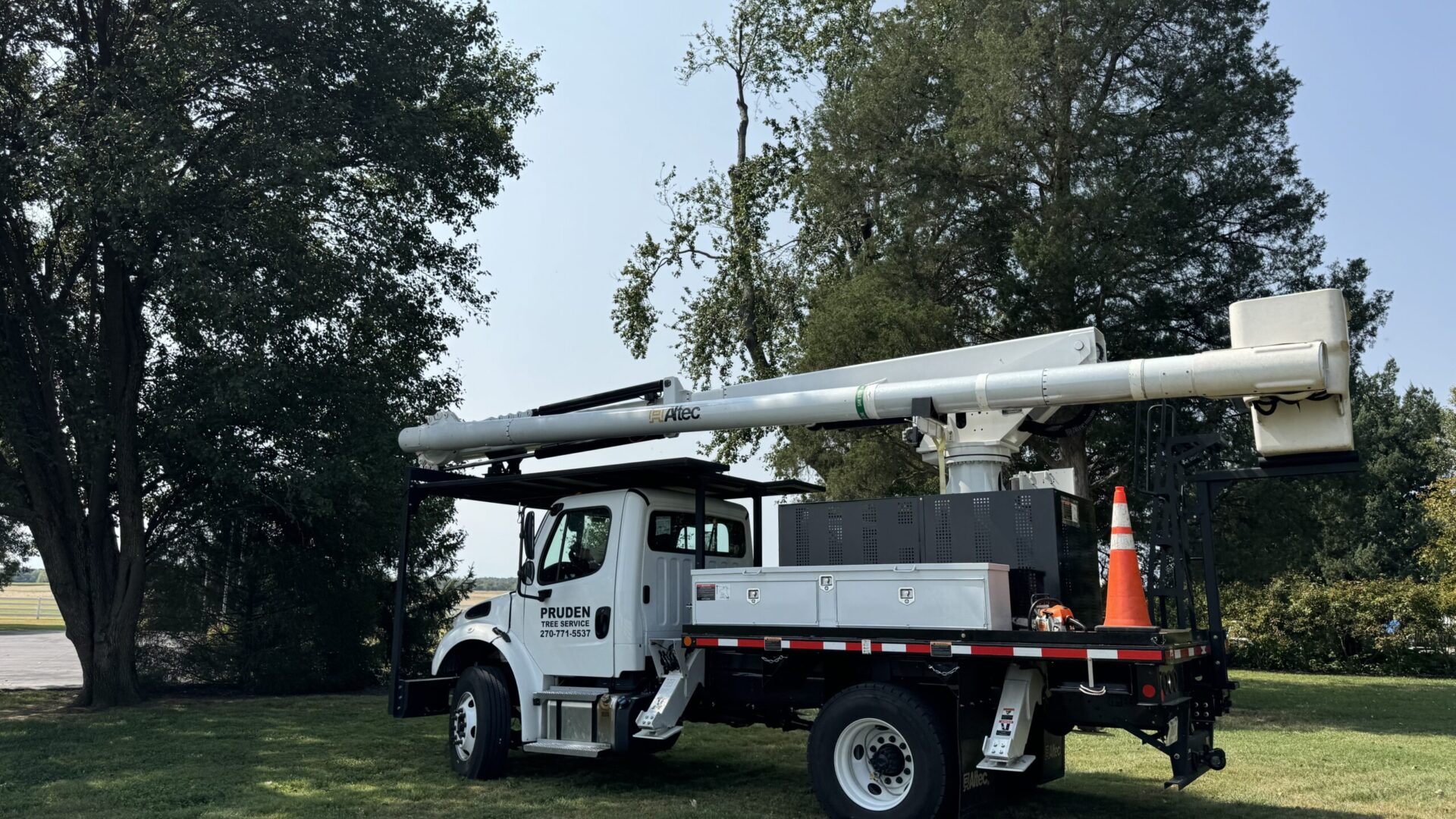 Pruden Tree Service bucket truck in front of large trees.